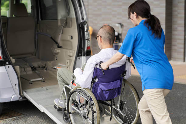 Caregiver helping man into wheelchair into accessible van